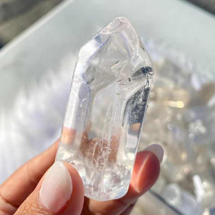 Clear crystal held in a hand with a blurred background