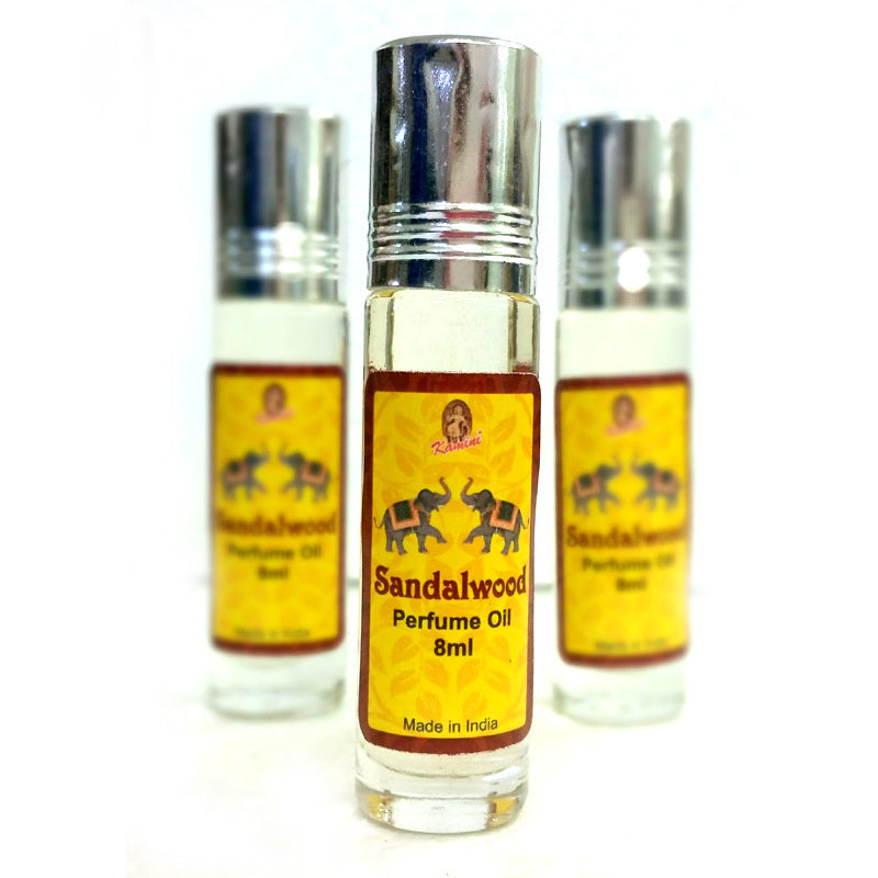 Three bottles of Sandalwood Perfume Oil with yellow labels and silver caps on a white background.
