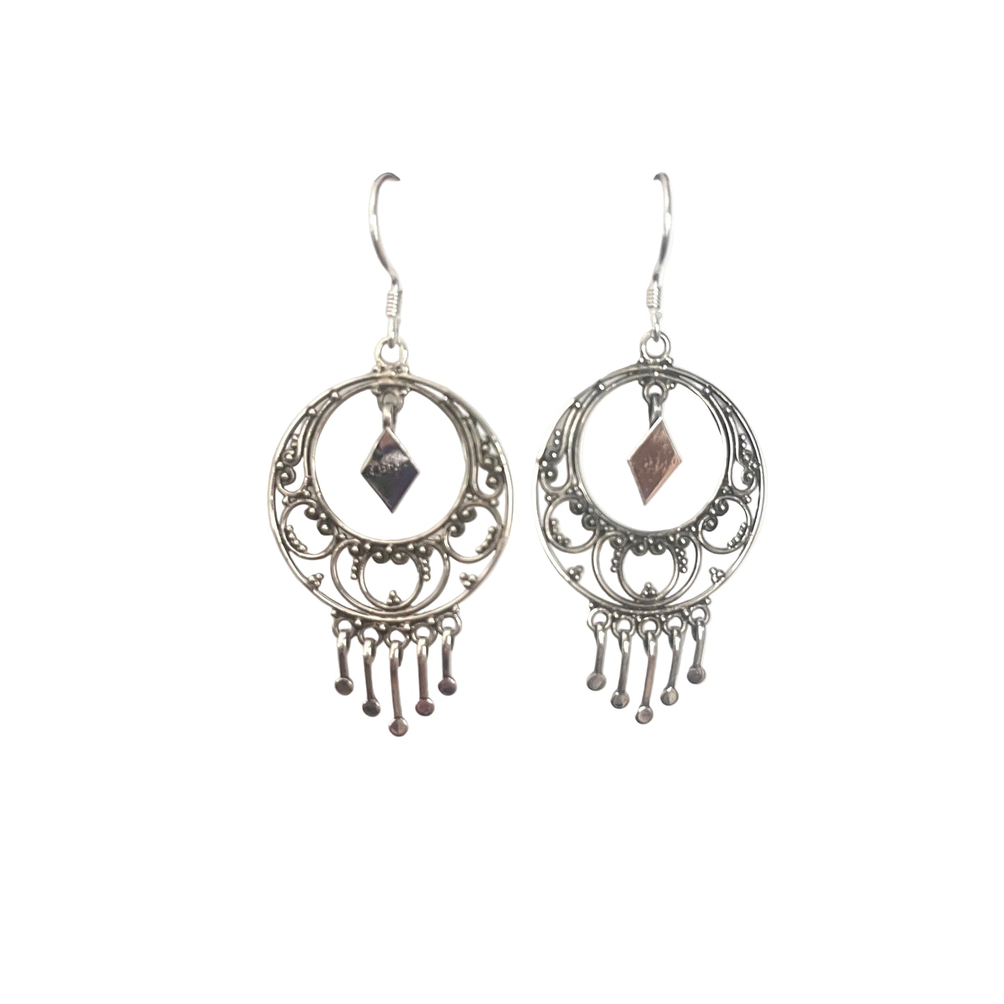 Pair of silver earrings with circular designs and dangling elements on a white surface.