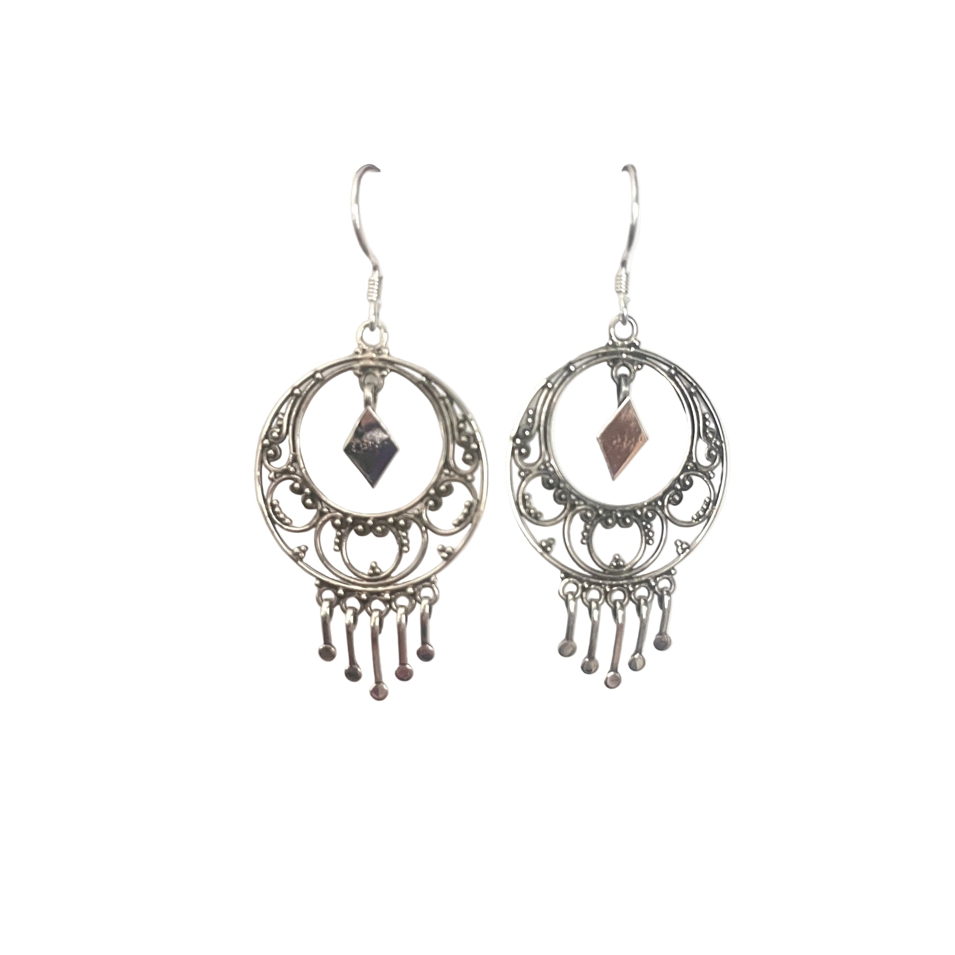 Pair of silver earrings with circular designs and dangling elements on a white surface.