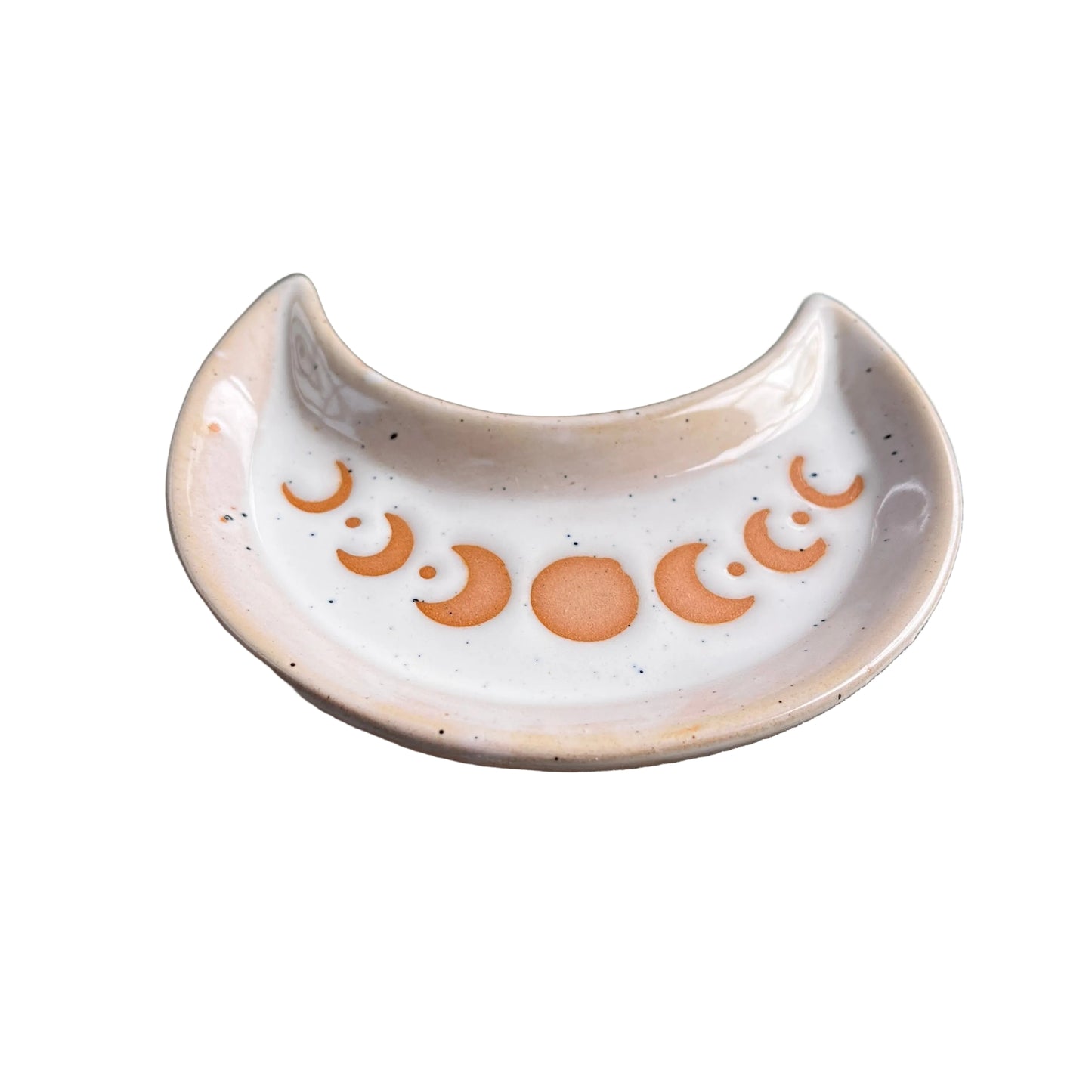 A small ceramic crescent-shaped dish with a moon phase design in terracotta orange on a speckled off-white glaze, resting on a white surface.