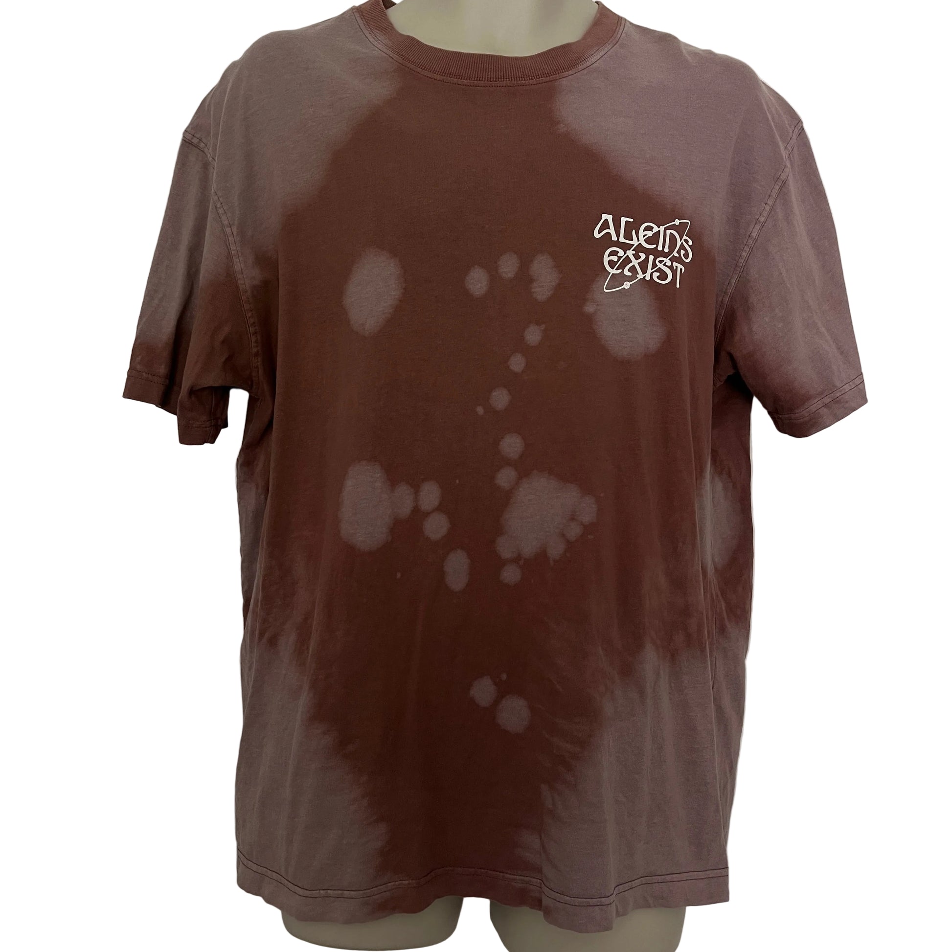 Brown t-shirt with splatter design and 'aliens Exist' text on a mannequin against a white door background.