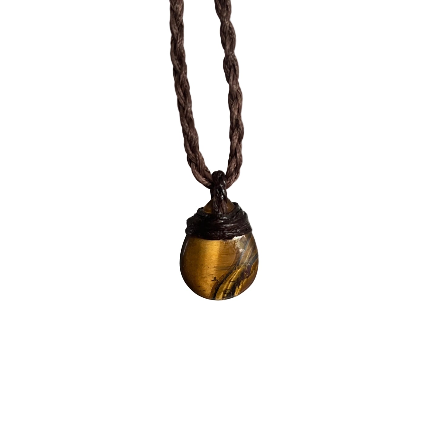 A small teardrop-shaped gold pendant with dark inclusions, hanging from a dark brown braided cord necklace against a softly blurred gray background.