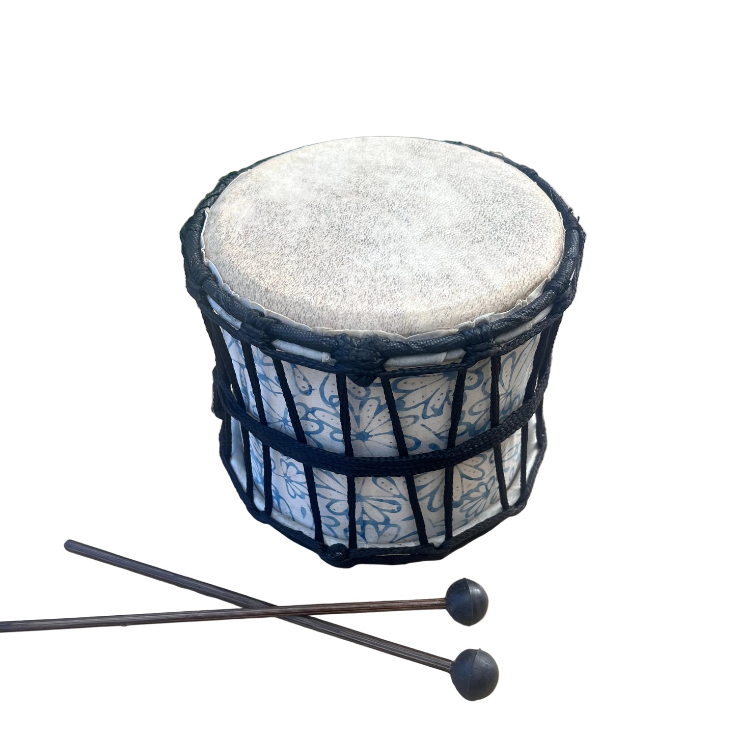 A hand drum with a beige drumhead, black rope tension, and a white body decorated with blue floral patterns, shown with two mallets in the foreground.