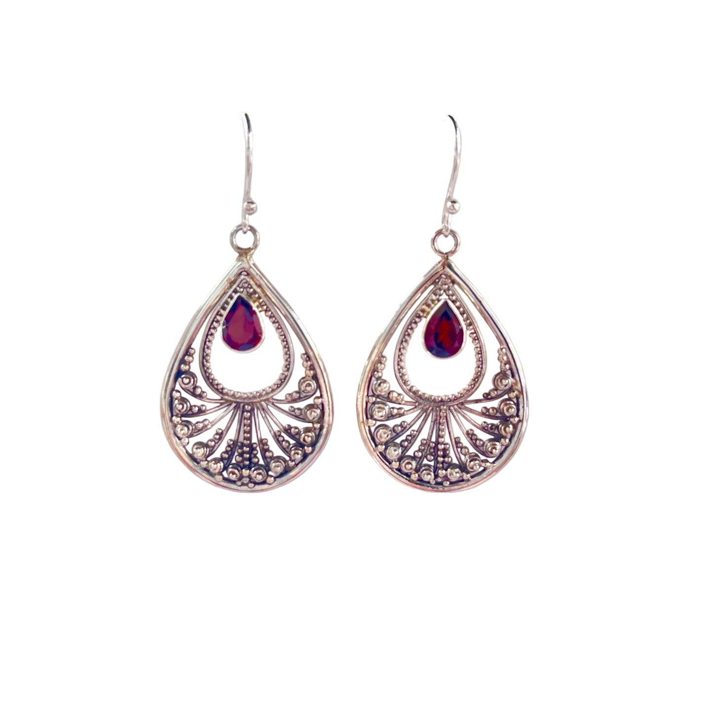Teardrop-shaped silver earrings with red gemstones on a white surface