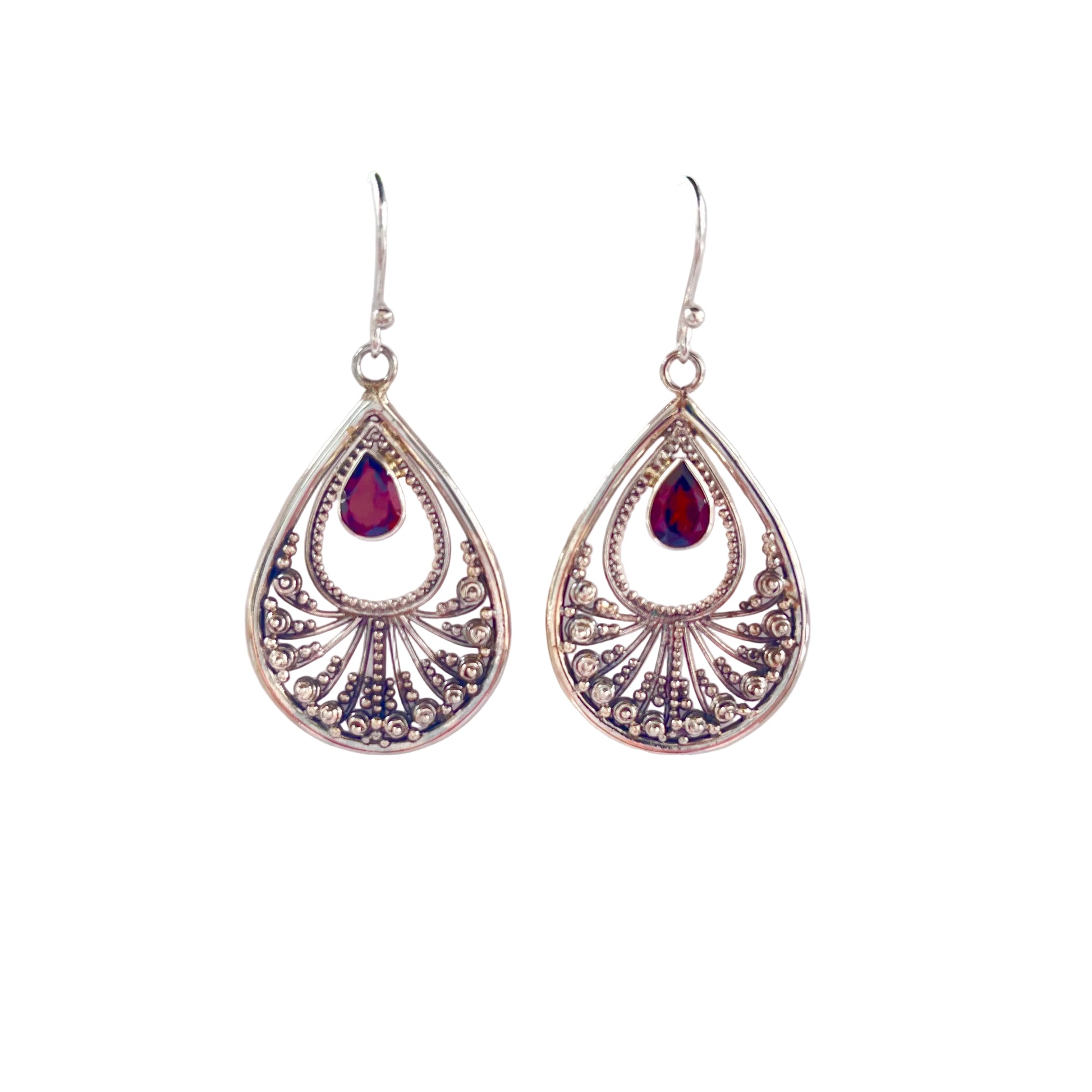 Teardrop-shaped silver earrings with red gemstones on a white surface