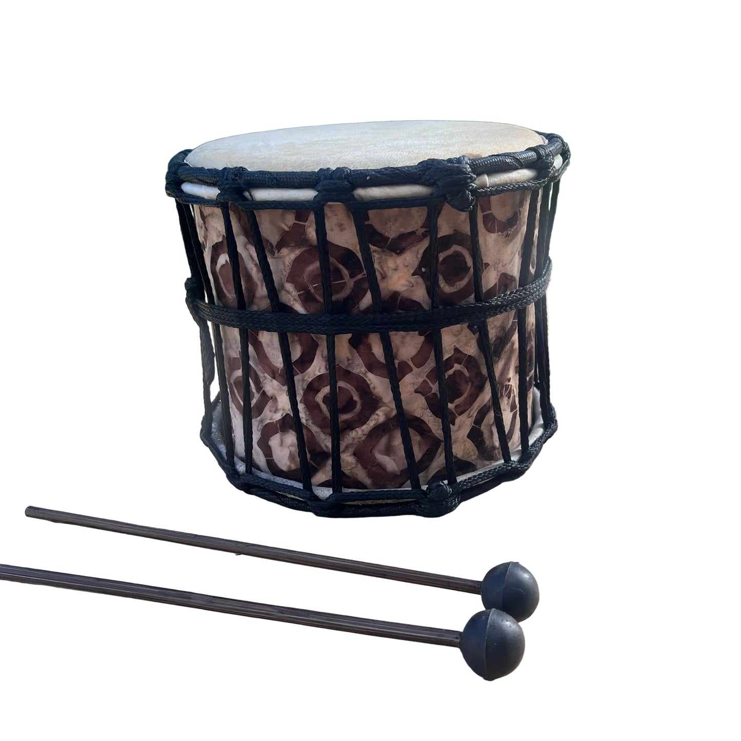 A hand drum with a brown and beige patterned body, black rope tensioning, and a light natural drumhead, with two mallets in front.