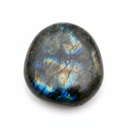 Labradorite stone held in a hand with a blurred green background