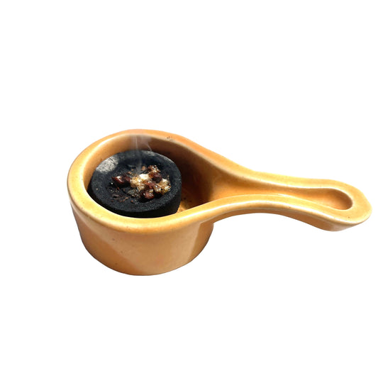 Small ceramic container with a handle on a light surface