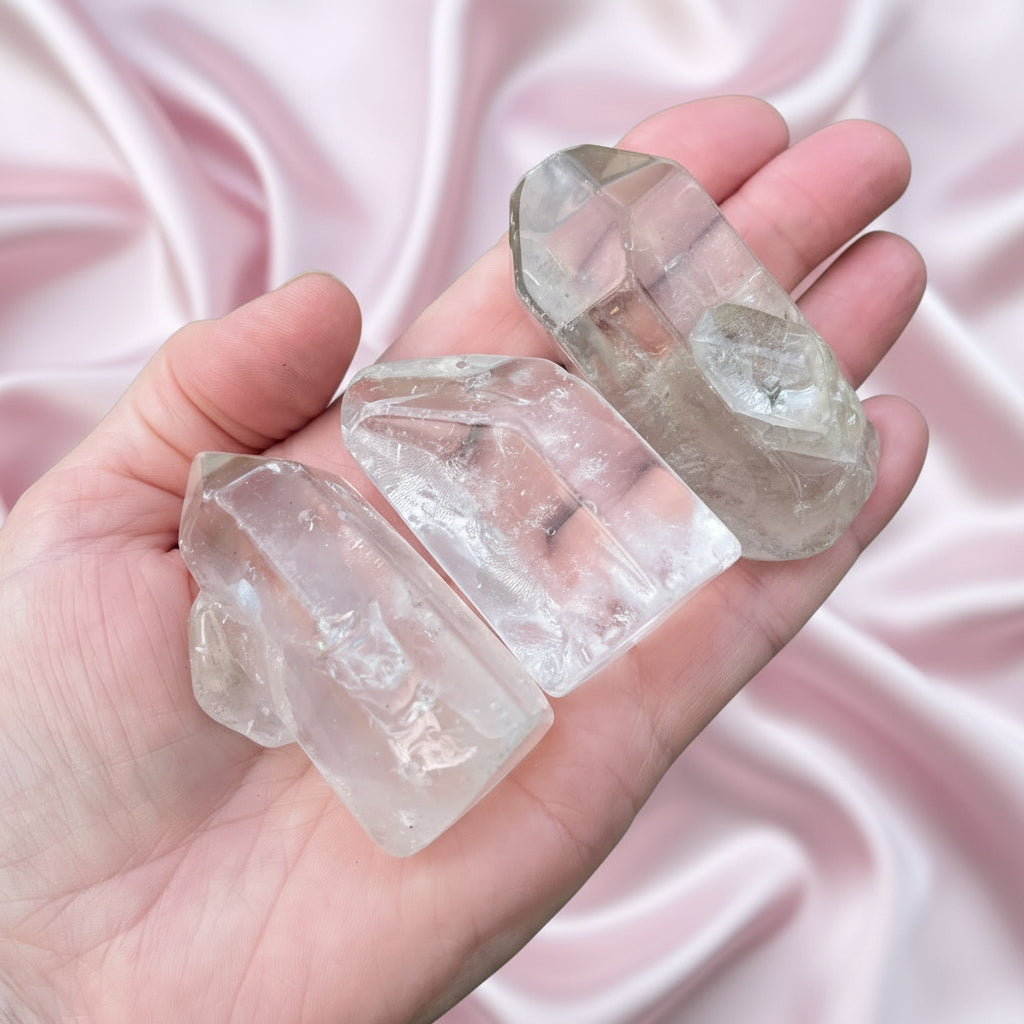 Hand holding three clear quartz crystals