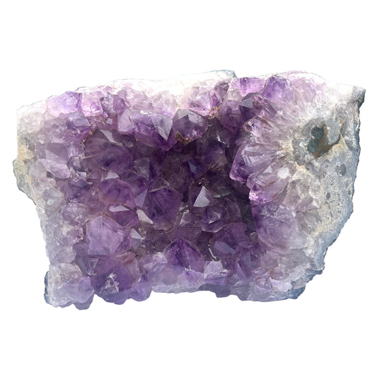 Amethyst crystal cluster on a white surface with a blurred background