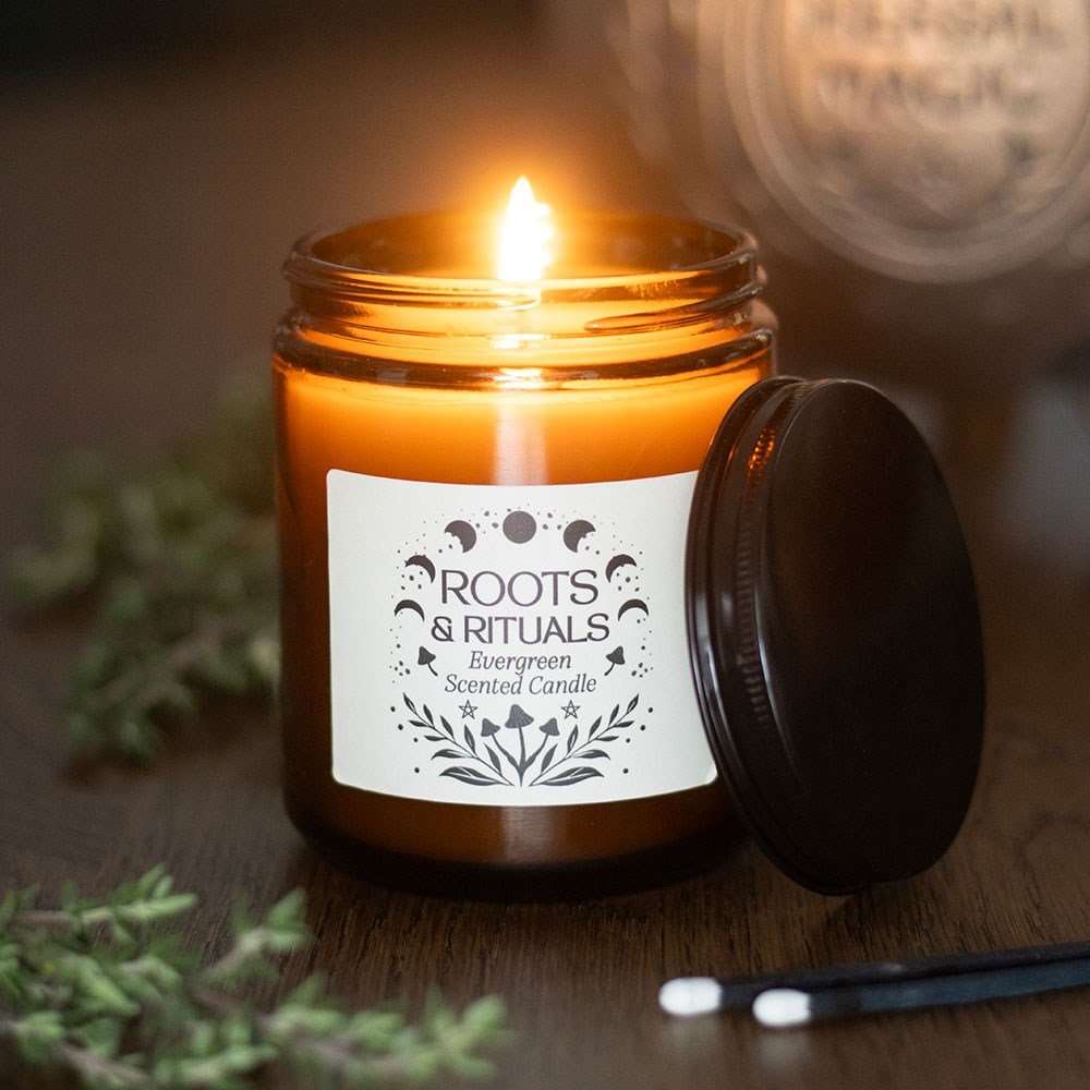 Candle in a jar with a label reading 'Roots & Rituals' on a wooden surface.