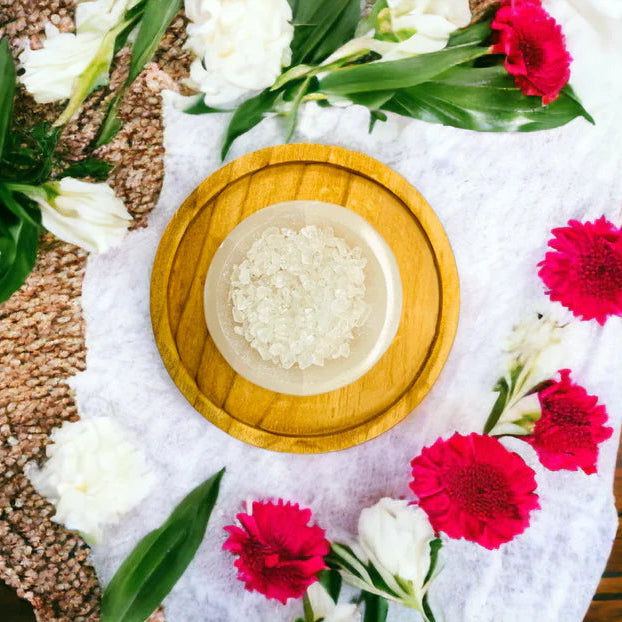 Decorative setting with clear quartz crystals, white flowers, and red flowers on a textured surface.