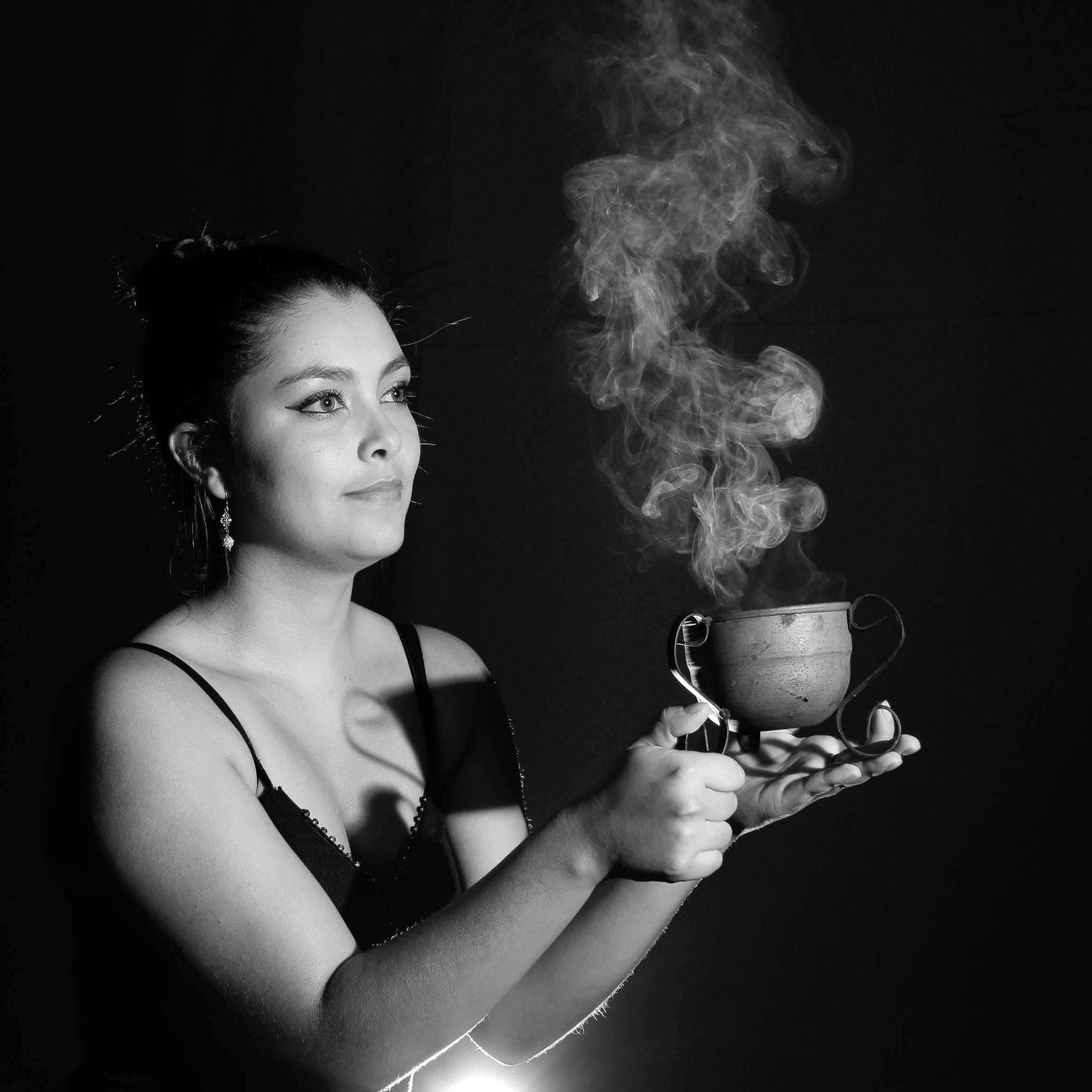Woman holding a steaming cup against a dark background