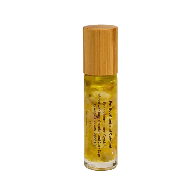 Roll-on bottle of essential oil with clear peach moonstone crystals with wooden cap on a neutral background
