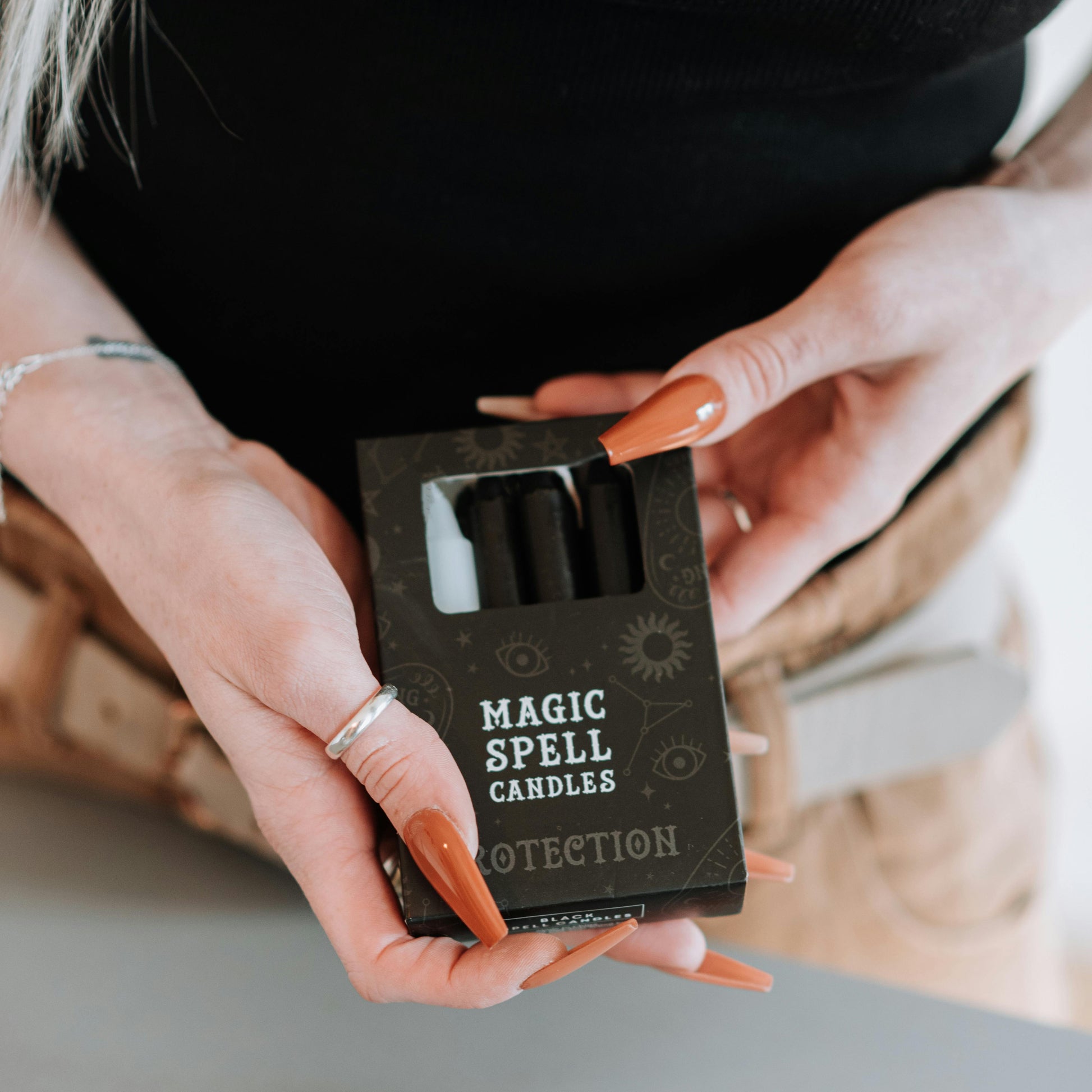 Person holding a box of 'Magic Spell Candles' with 'Protection' 