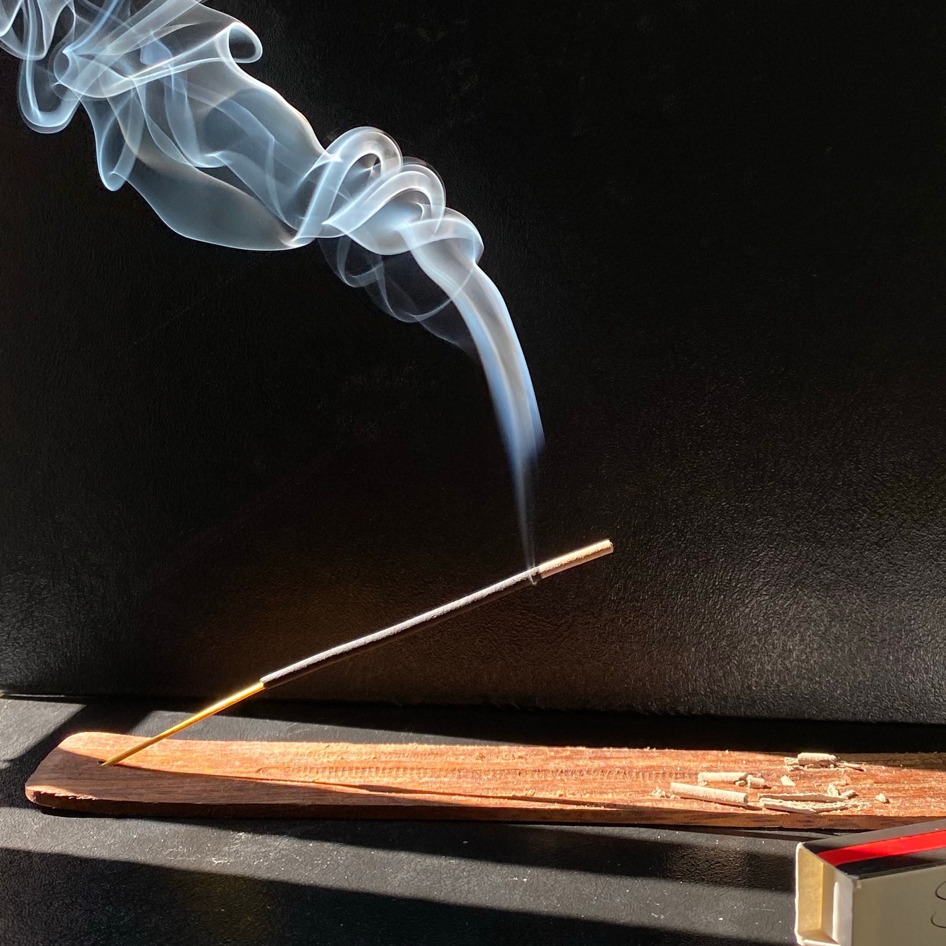 Incense stick with smoke against a black background