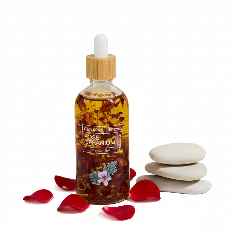 Bottle of 'Rose Geranium' essential oil with a wooden dropper on a neutral background